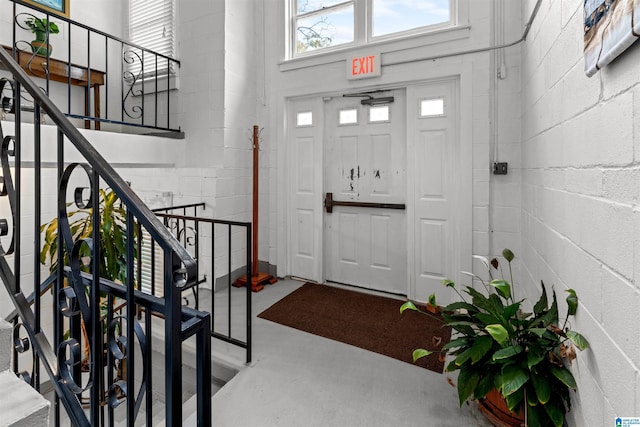 entryway with stairway, finished concrete floors, and concrete block wall