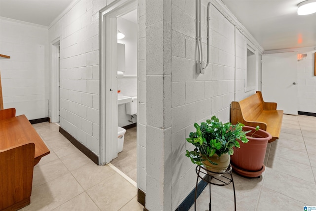 hall with tile patterned floors and concrete block wall