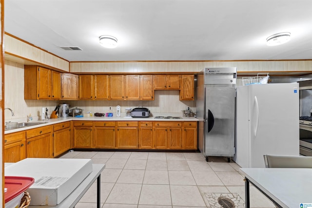 kitchen with visible vents, brown cabinets, white appliances, and a sink