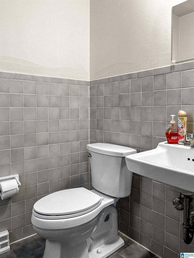 half bath with toilet and tile walls