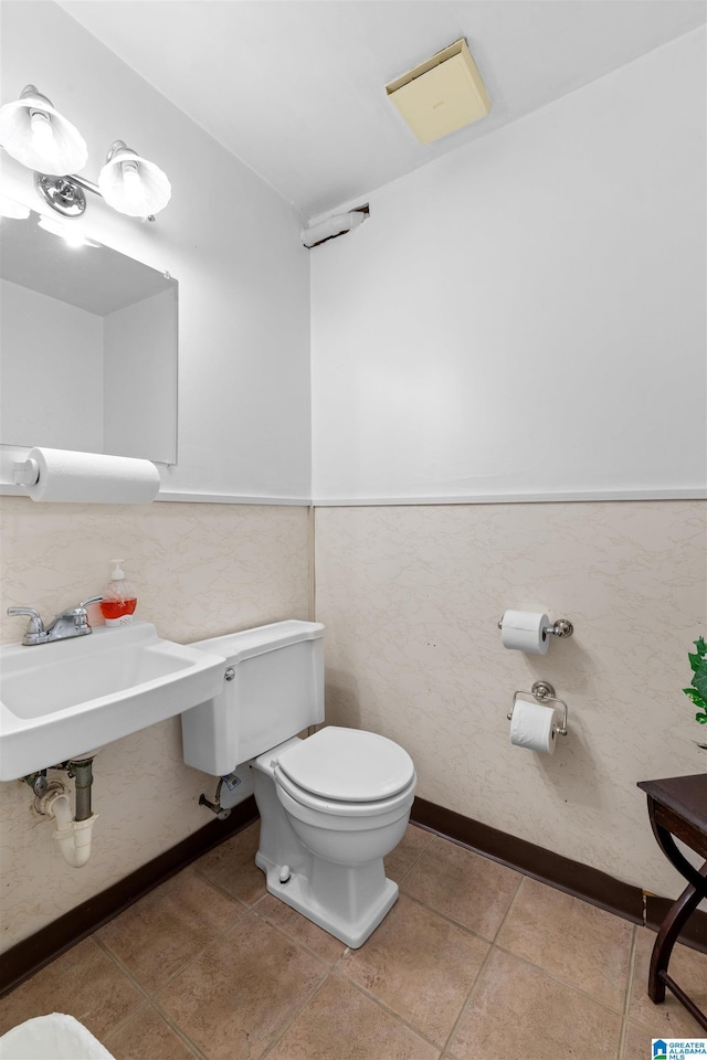 bathroom with tile patterned flooring, a wainscoted wall, toilet, tile walls, and a sink