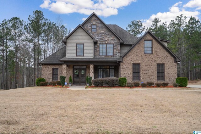 craftsman inspired home with brick siding, french doors, a front yard, and roof with shingles