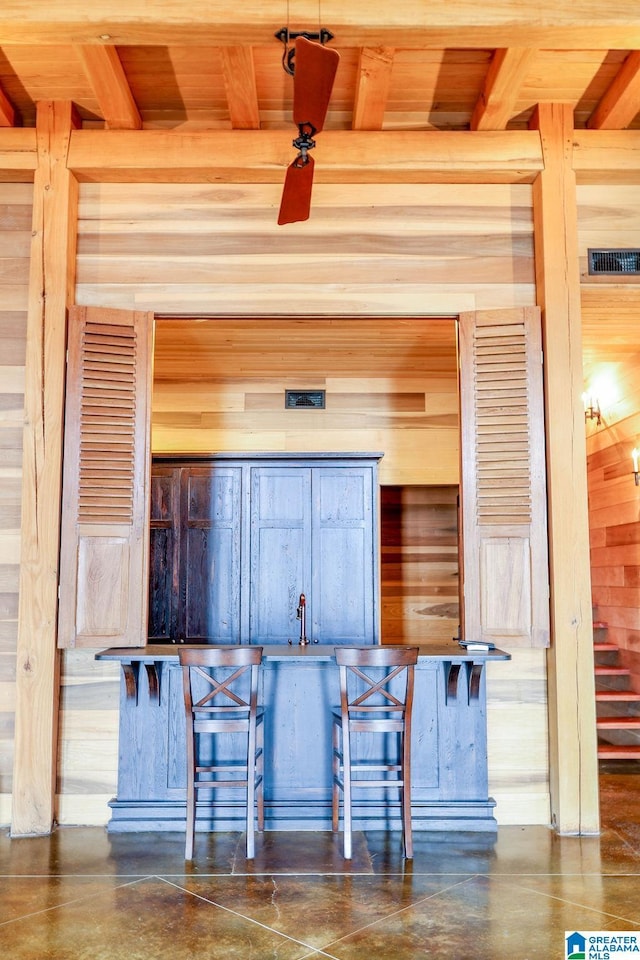 interior space featuring beam ceiling, visible vents, wood walls, and concrete flooring