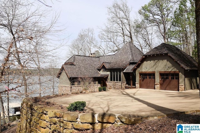 view of front of home featuring a garage, stone siding, and concrete driveway