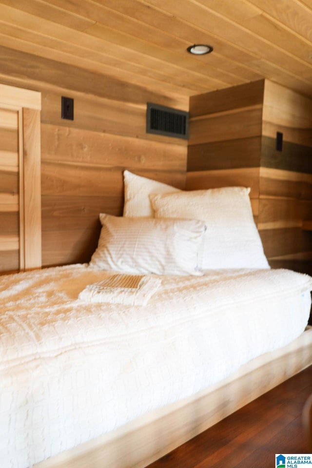 unfurnished bedroom featuring visible vents, wooden walls, wood finished floors, and wooden ceiling