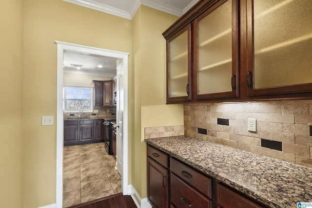 kitchen featuring dark stone counters, dark brown cabinetry, glass insert cabinets, crown molding, and tasteful backsplash