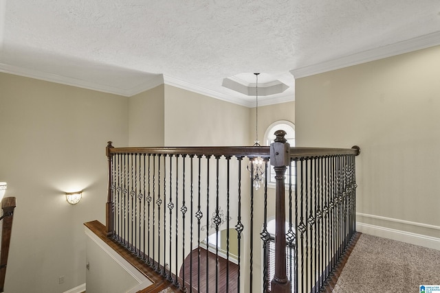 corridor with crown molding, carpet, baseboards, and a textured ceiling