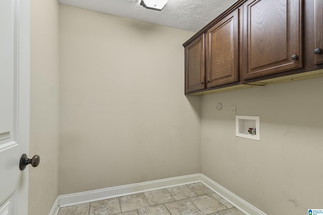 washroom with baseboards, cabinet space, a textured ceiling, and washer hookup