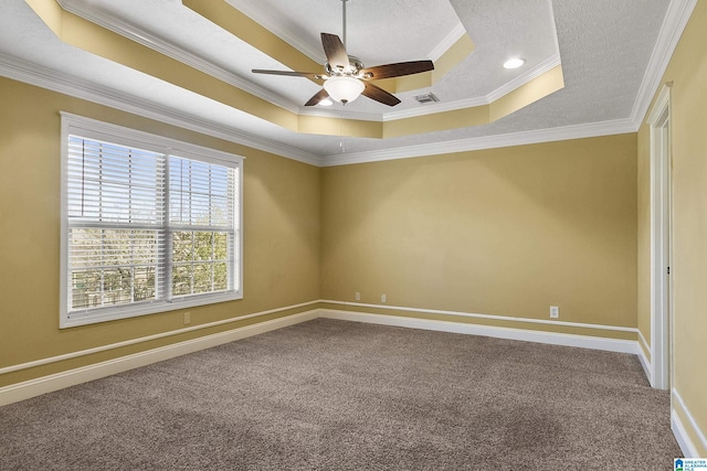 empty room with a tray ceiling, carpet, crown molding, baseboards, and ceiling fan