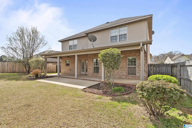 rear view of house featuring a yard, brick siding, a fenced backyard, and a patio area