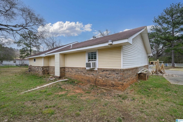 view of side of property with a yard, brick siding, and cooling unit