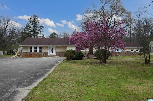 view of front of property featuring stone siding, concrete driveway, and a front lawn