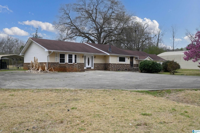 single story home with brick siding, a detached carport, concrete driveway, and a front yard