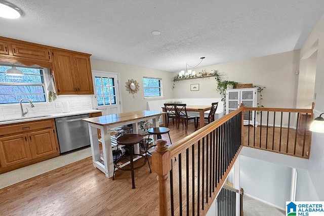 kitchen with light wood finished floors, dishwasher, light countertops, decorative backsplash, and a sink