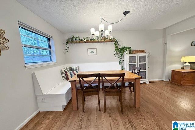 dining room with a notable chandelier, a textured ceiling, baseboards, and wood finished floors