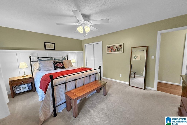 bedroom with a textured ceiling, a ceiling fan, baseboards, a closet, and light carpet