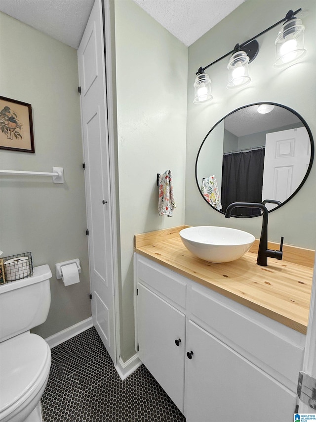 full bath with vanity, toilet, baseboards, and a textured ceiling