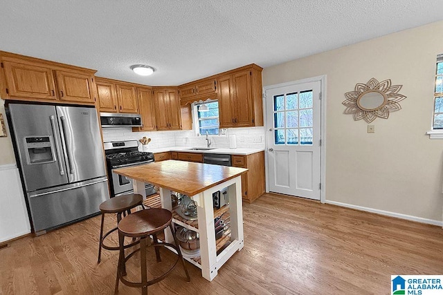 kitchen featuring a sink, light wood-style flooring, tasteful backsplash, and stainless steel appliances