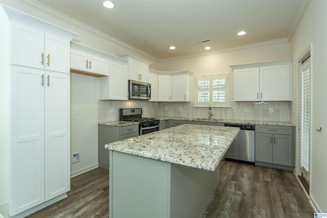 kitchen with visible vents, a kitchen island, a sink, stainless steel appliances, and dark wood-type flooring