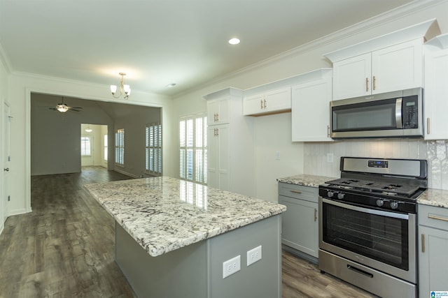 kitchen featuring a center island, ornamental molding, light stone counters, decorative backsplash, and stainless steel appliances