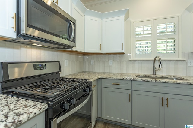 kitchen featuring a sink, light stone counters, white cabinetry, appliances with stainless steel finishes, and decorative backsplash