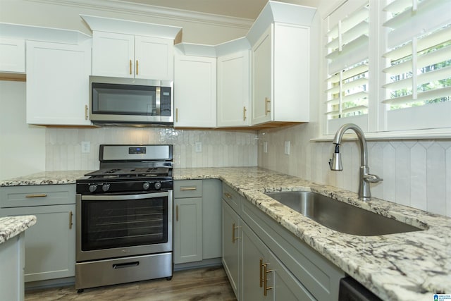 kitchen with backsplash, appliances with stainless steel finishes, light stone countertops, and a sink