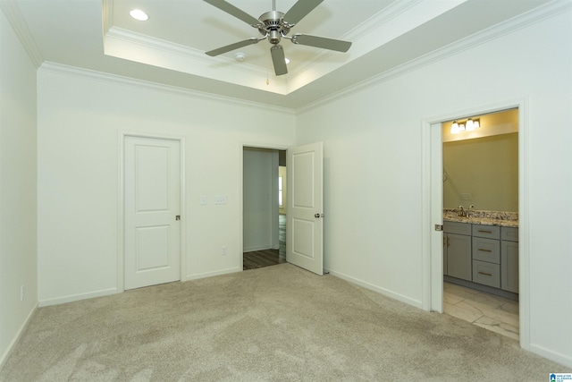 unfurnished bedroom featuring connected bathroom, a raised ceiling, light colored carpet, and crown molding