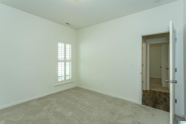 spare room featuring baseboards, visible vents, and carpet floors