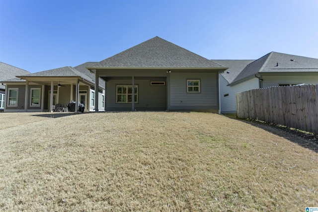 rear view of house with a shingled roof, fence, a yard, a patio area, and a ceiling fan