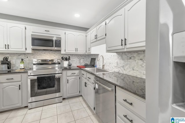 kitchen with a sink, light tile patterned flooring, backsplash, and stainless steel appliances