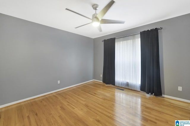 unfurnished room with wood finished floors, a ceiling fan, baseboards, and visible vents