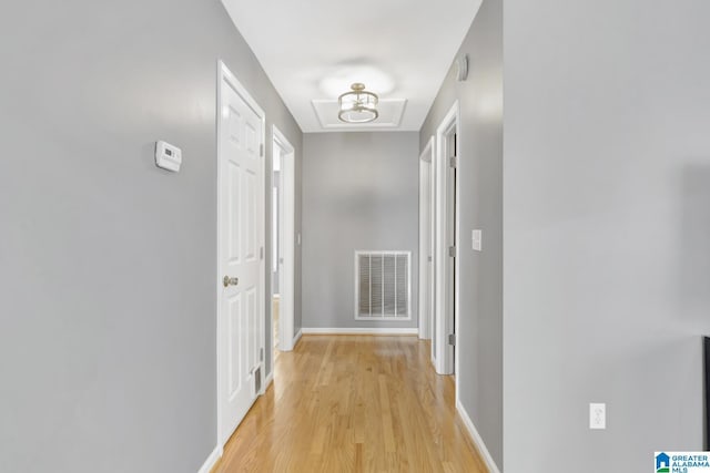 hallway with light wood-type flooring, visible vents, and baseboards