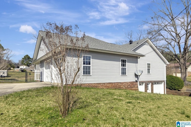 view of side of home with fence, driveway, roof with shingles, an attached garage, and a lawn