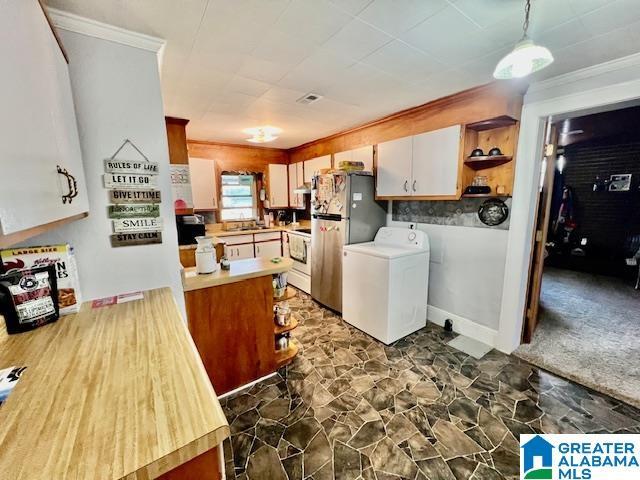 kitchen with washer / dryer, open shelves, freestanding refrigerator, light countertops, and crown molding