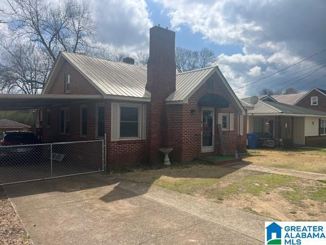 view of front of home with brick siding, driveway, a chimney, and a carport