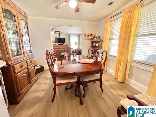 dining room with light wood-style flooring, a ceiling fan, and ornamental molding