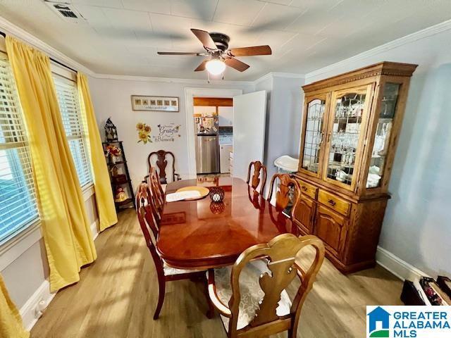 dining space featuring visible vents, crown molding, and light wood-type flooring