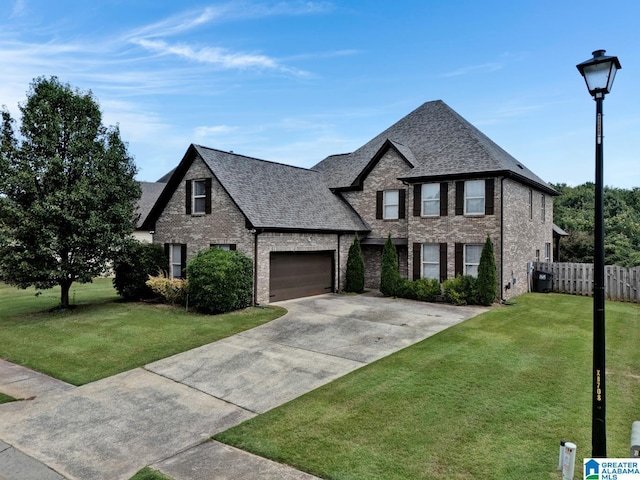 view of front facade featuring a front lawn, fence, brick siding, and driveway