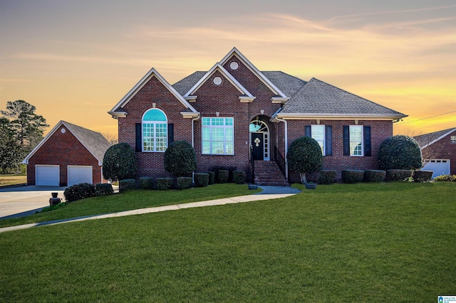 view of front of property featuring a detached garage, brick siding, and a lawn