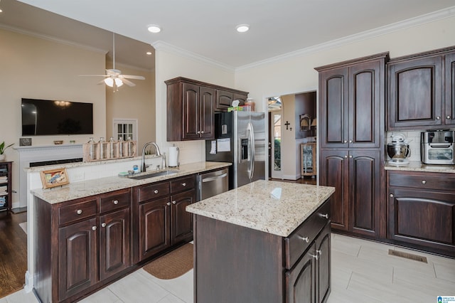 kitchen featuring a ceiling fan, a sink, a kitchen island, backsplash, and stainless steel appliances