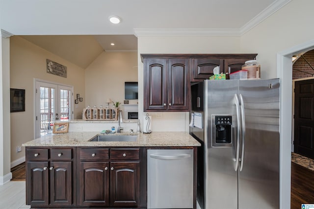 kitchen with dark brown cabinetry, decorative backsplash, appliances with stainless steel finishes, a peninsula, and a sink