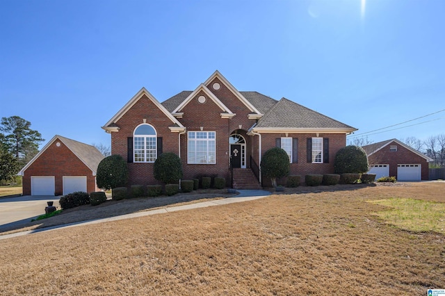 view of front of property featuring brick siding, a front yard, a detached garage, and an outdoor structure