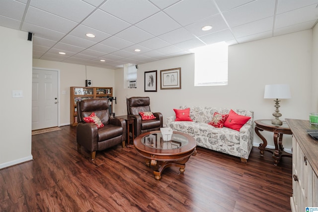 living area with a drop ceiling, recessed lighting, baseboards, and wood finished floors