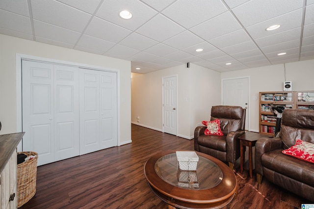 living room featuring a drop ceiling, recessed lighting, baseboards, and dark wood-style flooring