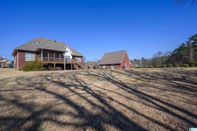 back of property with stairs, a yard, brick siding, and a wooden deck