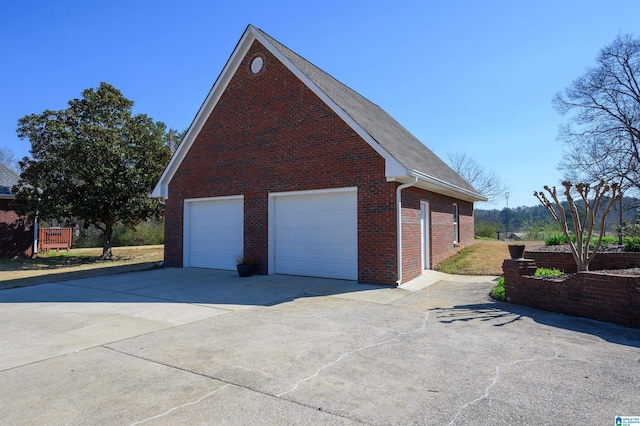 view of property exterior featuring an outbuilding, driveway, brick siding, and a garage