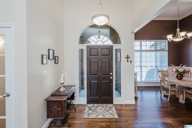 entryway with a high ceiling, a notable chandelier, wood finished floors, and baseboards