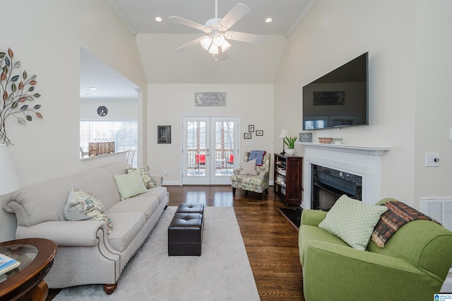 living area featuring dark wood-type flooring, a high ceiling, ceiling fan, and a fireplace