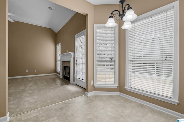 unfurnished living room with baseboards, a tiled fireplace, vaulted ceiling, carpet floors, and a notable chandelier