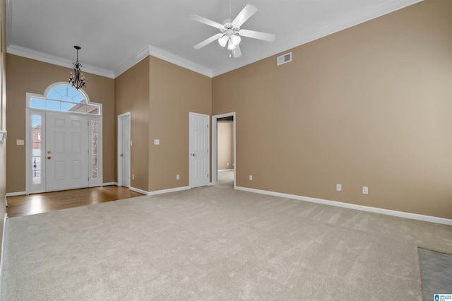 carpeted foyer featuring visible vents, a high ceiling, crown molding, baseboards, and ceiling fan